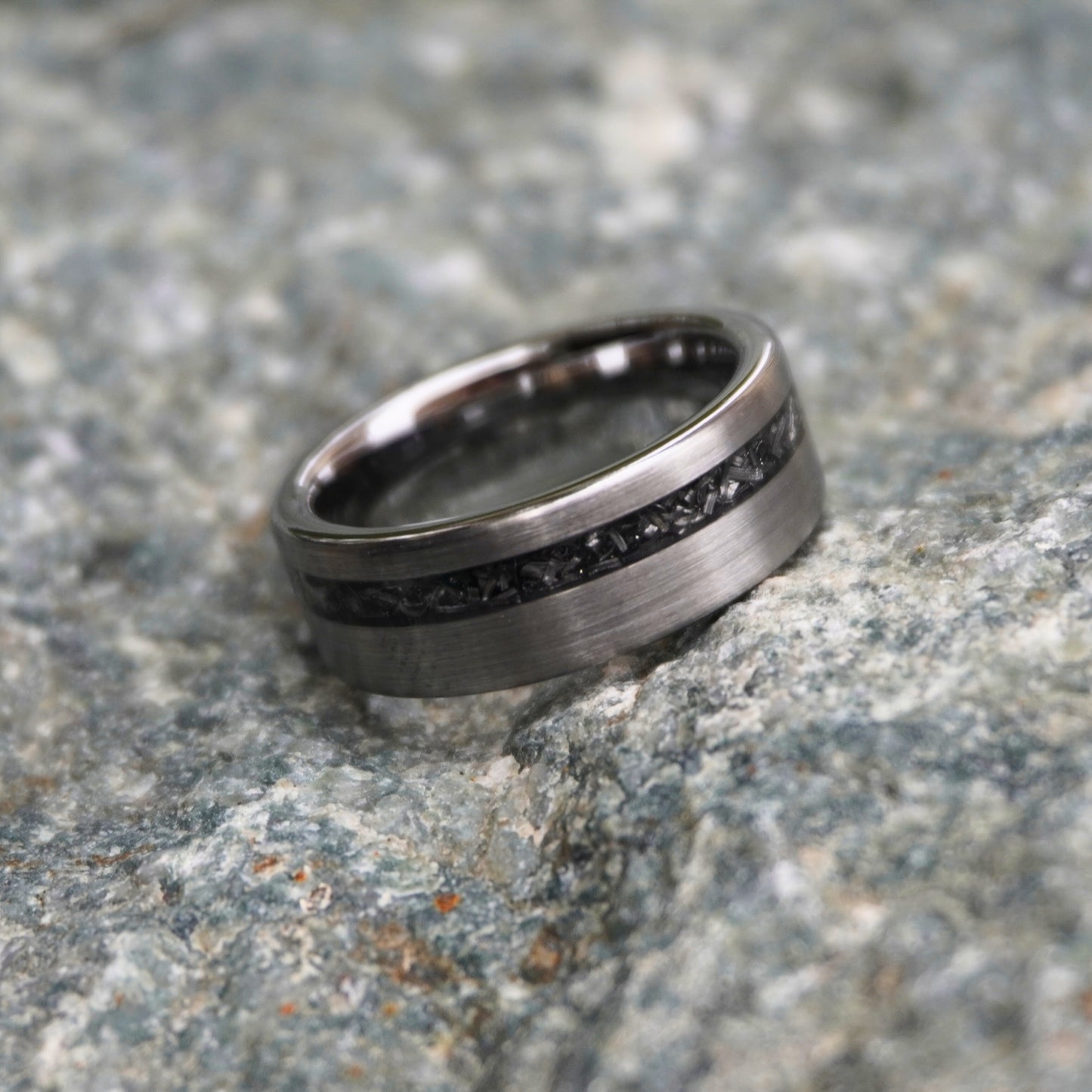 Durable 8mm cosmic ring with engravable black inlay by Forge and Lumber, displayed on textured stone surface.