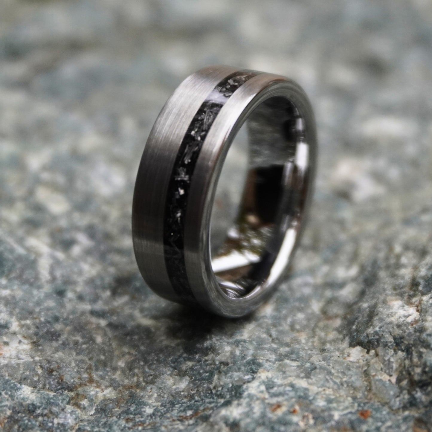 Durable 8mm cosmic ring with engravable black inlay by Forge and Lumber, shown on textured stone background.