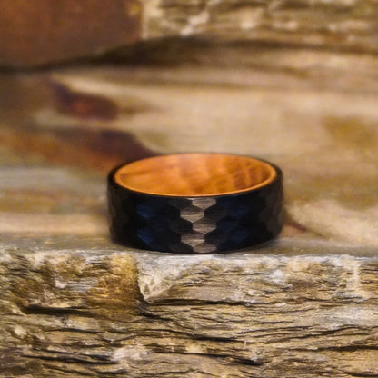 Black 8mm flat ring with a textured surface and wooden interior by Forge and Lumber.