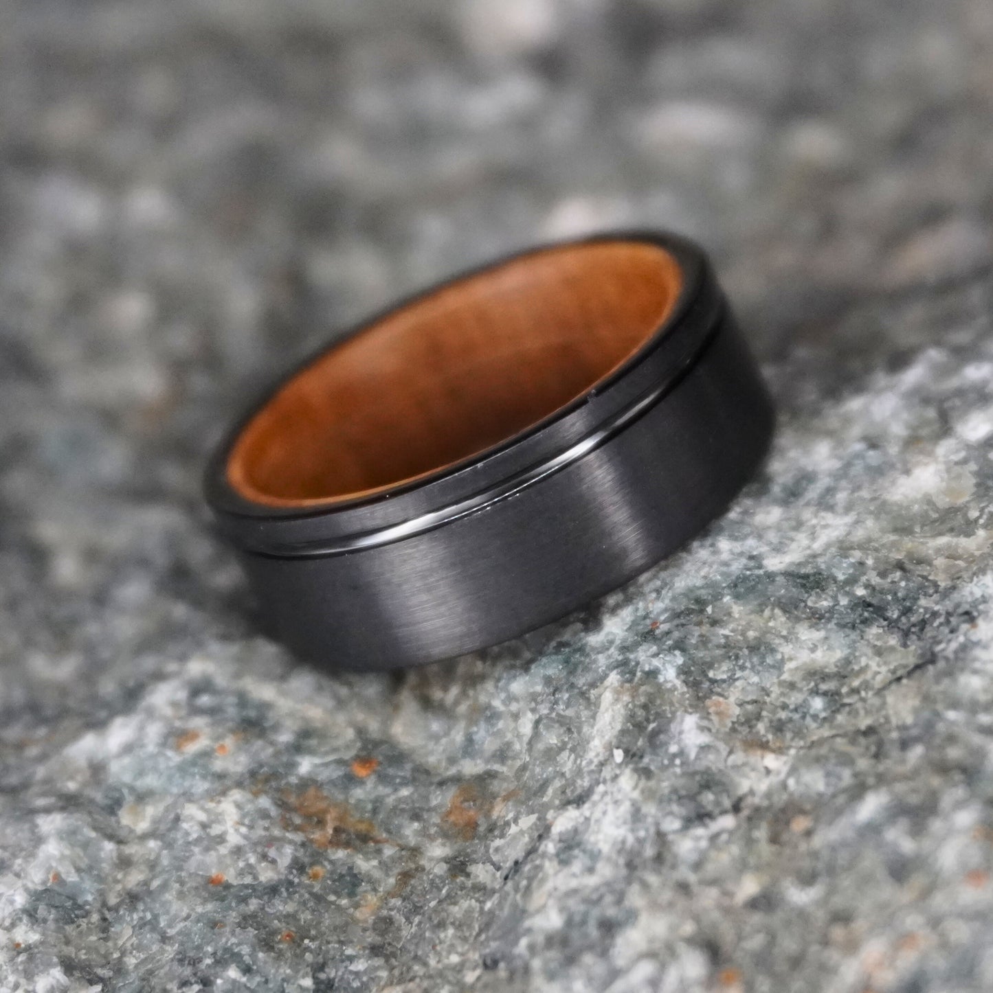 Black brushed 8mm barrel ring with wooden interior by Forge and Lumber. Available in UK sizes M, N, O.
