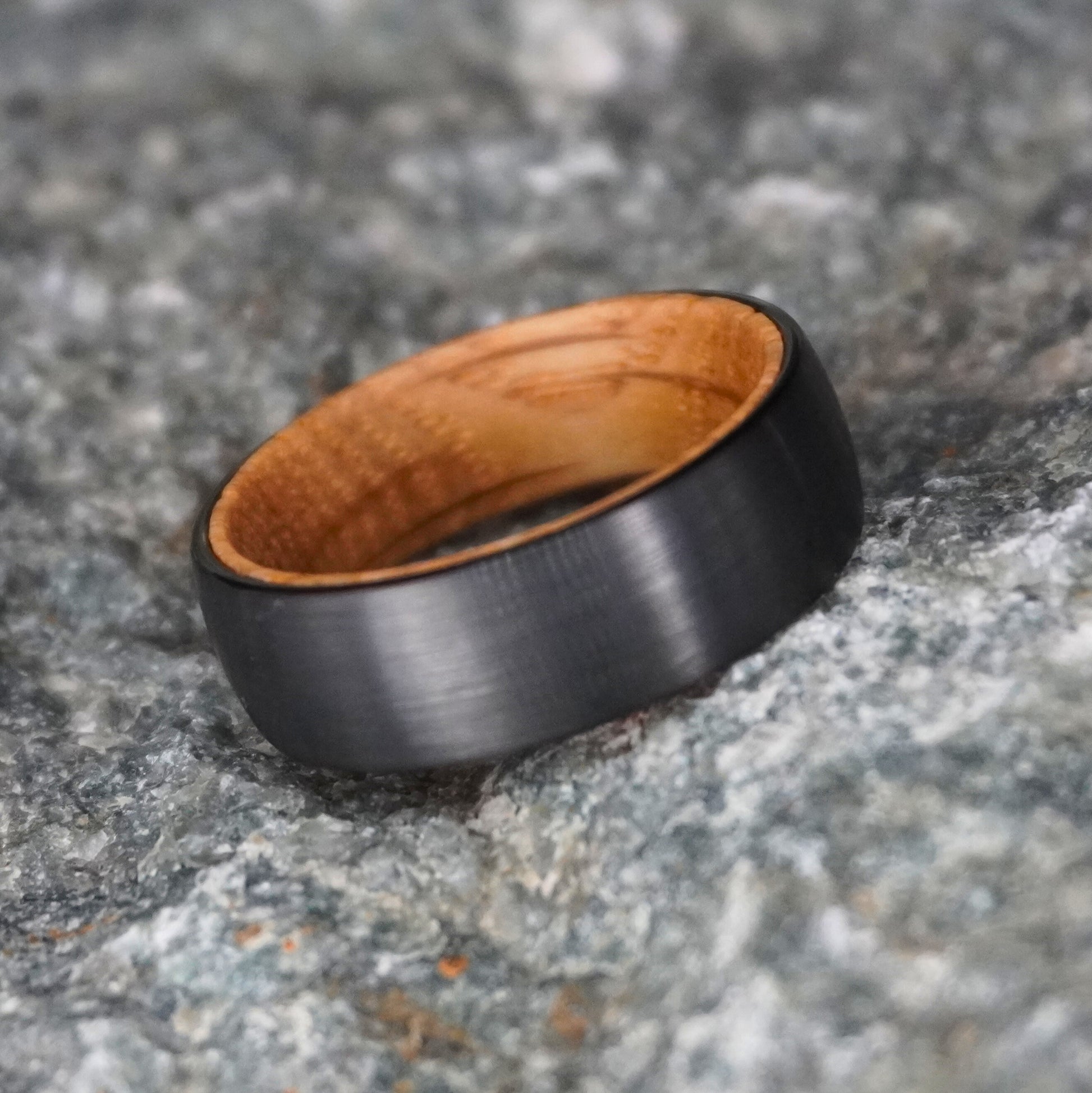 Black barrel wedding band with a wooden interior by Forge and Lumber, available in sizes UK M, N, O.