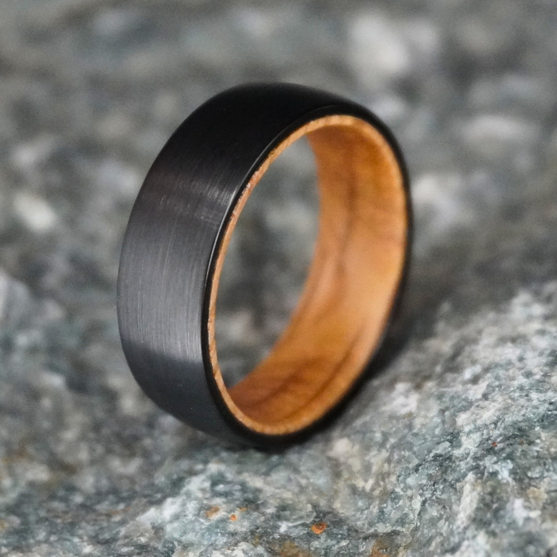 Black barrel wedding band with a brushed finish and wooden interior by Forge and Lumber. Available in sizes UK M to O.