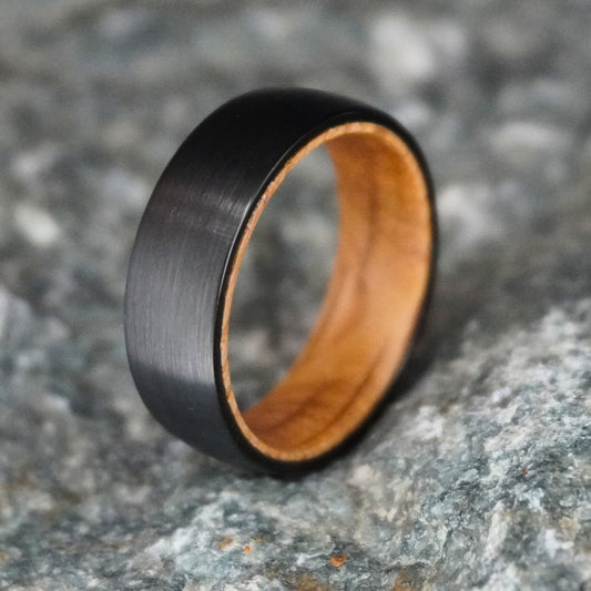 Black barrel wedding band with a brushed finish and wooden interior by Forge and Lumber. Available in sizes UK M to O.
