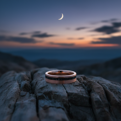 Rose gold and black 6mm wedding band from the Apollo collection by Forge and Lumber, set against a sunset backdrop.