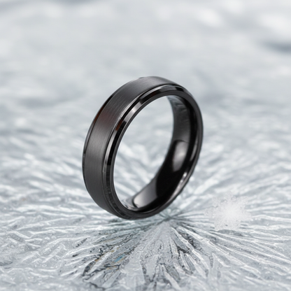 Sleek black ring with a brushed finish, elegantly displayed on a textured icy surface.