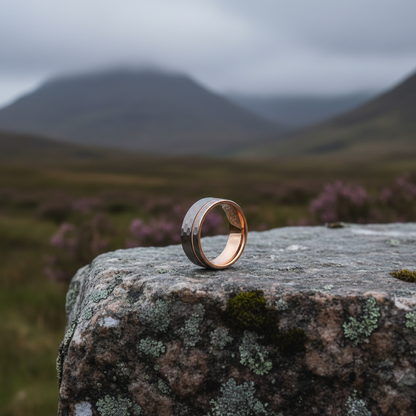 Engravable flat gold ring by Forge and Lumber placed on a textured stone in a natural landscape.