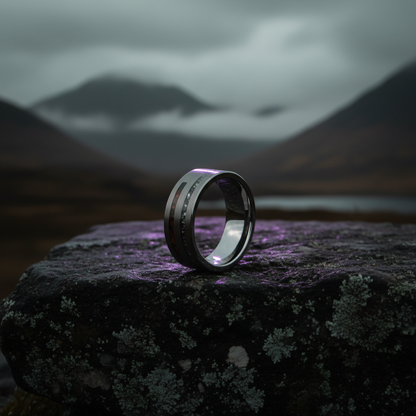 Silver wedding band with cosmic dinosaur bone inlay by Forge and Lumber, set against a dramatic mountain backdrop.