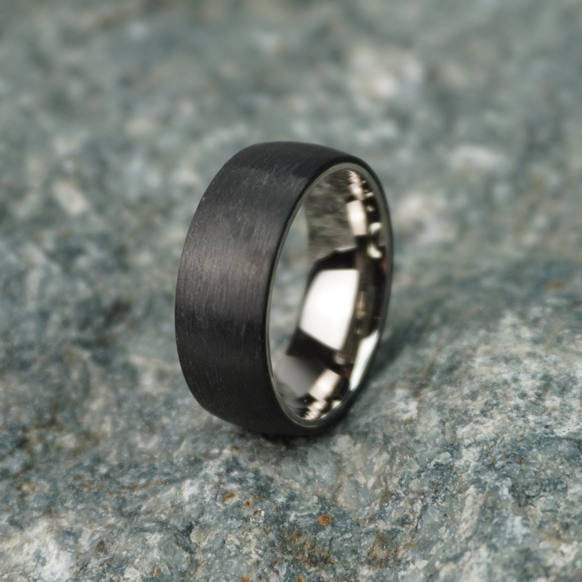 Black 8mm carbon fiber ring with a brushed finish by Forge and Lumber, suitable for weddings and anniversaries.